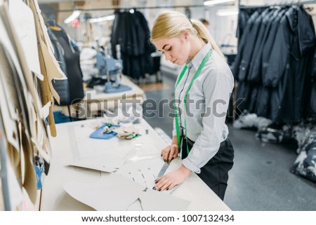 Clothes designer measures a pattern, sewing