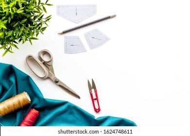 Clothes designer work desk. Pattern, scissors, thread, textile on white background top-down copy space