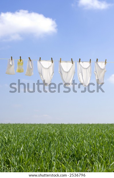 Clothes drying in the summer breeze on clear blue\
sky with soft clouds