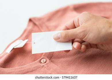Clothes, Fashion, People And Shopping Concept - Close Up Of Hand Holding Price Tag Of Clothing Item