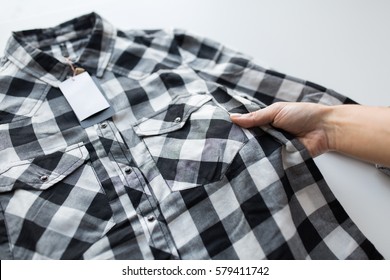 Clothes, Fashion, People And Shopping Concept - Close Up Of Hand Holding Checkered Shirt With Price Tag