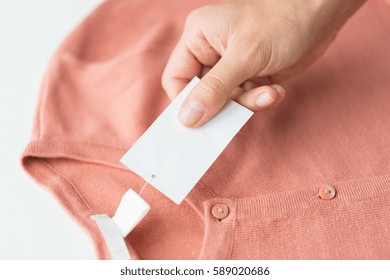 Clothes, Fashion, People And Shopping Concept - Close Up Of Hand Holding Price Tag Of Clothing Item