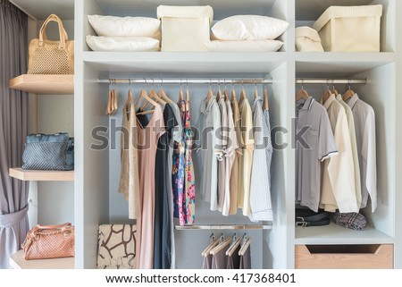 clothes hanging on rail in wooden closet at home