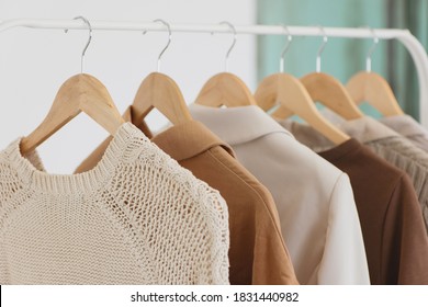 Clothes hanging on wooden hangers in fashion store closeup. - Powered by Shutterstock