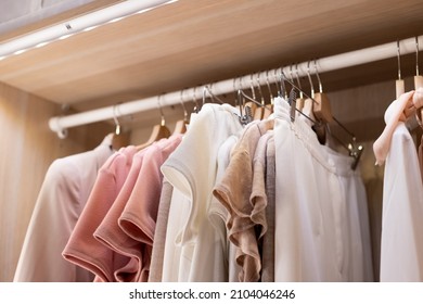 Clothes on a rail in a wardrobe. Seasonal capsule for easy dressing, order in things, cleaning out.Colorful casual clothes hang on hangers.Wardrobe, dressing room filled with clothes, shoes. storage - Shutterstock ID 2104046246