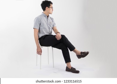 Clothes, People, Luxury, Background, Fashion, Style Concept -   Young Asian Men Sitting On White Chair With Gray Oxford Shirt Short Sleeve And Black Slack Pants On White Background