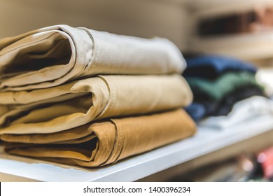 clothes ,sale, shopping, fashion, style concept - Stack of chino pants ,Cream , Brown and khaki color, in the shopping mall - Shutterstock ID 1400396234