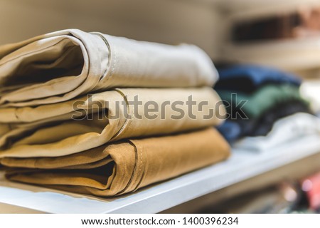 clothes ,sale, shopping, fashion, style concept - Stack of chino pants ,Cream , Brown and khaki color, in the shopping mall