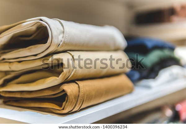 clothes ,sale, shopping, fashion, style concept -\
Stack of chino pants ,Cream , Brown and khaki color, in the\
shopping mall