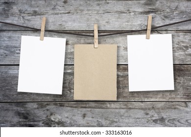 clothespin hanging with blank paper on wooden background 