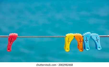 Clothespins On Empty Clothes Line, Blur Blue Color Background. Colorful Plastic Pins Hanging On Boat Stainless Rail. Summer Vacations And Sailing, Clothes Wash And Dry. Space, Advertise Template