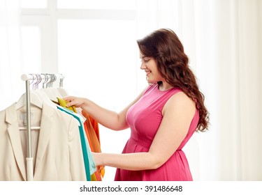 Clothing, Fashion, Style And People Concept - Happy Plus Size Woman Choosing Clothes At Home Wardrobe