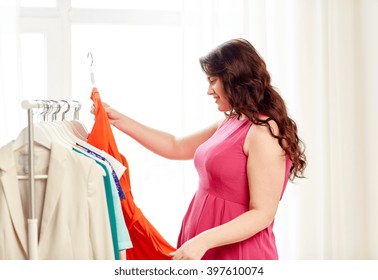 Clothing, Fashion, Style And People Concept - Happy Plus Size Woman Choosing Clothes At Home Wardrobe