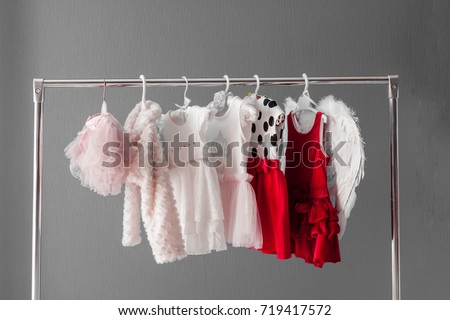 Clothing for a little girl on a clothes rack in a wardrobe