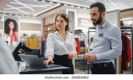 Clothing Store: Businesswoman Uses Laptop Computer, Talks To Visual Merchandising Specialist, Collaborate To Create Stylish Collection. Business Owner's Fashion Shop: Sales Manager Talks To Designer