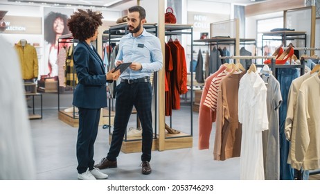 Clothing Store: Businesswoman Uses Tablet Computer, Talks To Visual Merchandising Specialist, Collaborate To Create Stylish Collection. Small Business Fashion Shop Sales Manager Talks To Designer.