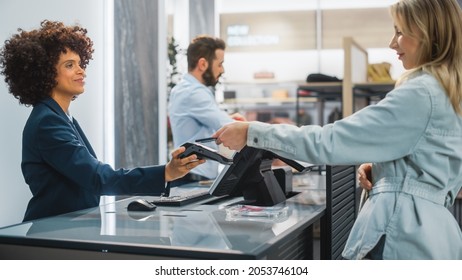 Clothing Store Checkout Cashier Counter: Woman And Male Retail Sales Managers Accept NFC Smartphone Payment From A Young Stylish Female Customer For New Stylish Clothes.