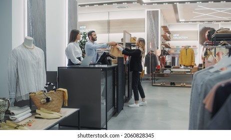 Clothing Store Checkout Cashier Counter: Beautiful Young Woman Buys Blouse from Friendly Retail Sales assistant, Receiving Bag with Purchases. Trendy Fashion Shop with of Designer Brands