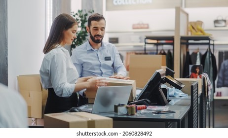 Clothing Store Checkout Cashier Counter: Female And Male Retail Sales Managers Carefully Packing Online Ordered Clothes Into Boxes. Fashionable Shop, With Stylish Brand Designs Available On Internet