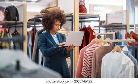 Clothing Store: Female Merchandising Manager Uses Laptop Computer To Create Stylish Fashion Collection. Professional Shop Sales Retail Assistant Checks Stock. Small Business Owner Orders Mall Items.