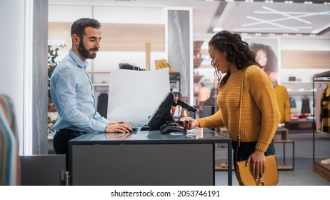 Clothing Store: Young Woman at Counter Buys Clothes from Friendly Retail Sales Assistant, Paying with Contactless NFC Smartphone Touching Terminal. Trendy Fashion Shop with Designer Brands.