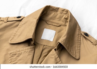 Clothing Tag, Label Blank Mockup Template, To Place Your Design. On A Beige Trench Coat With Black Buttons.