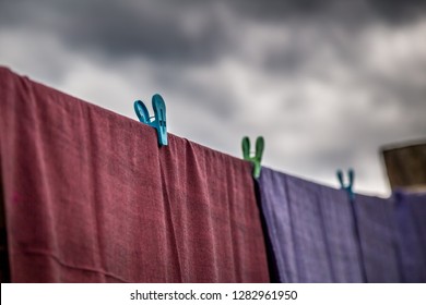 Clothing that has recently been washed is hung along the line to dry on clothes line with plastic clothespin with raining black cloud and storm coming    - Shutterstock ID 1282961950