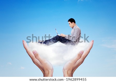Cloud computing concept. Close up of young man working with a laptop while sitting on a hand with white cloud