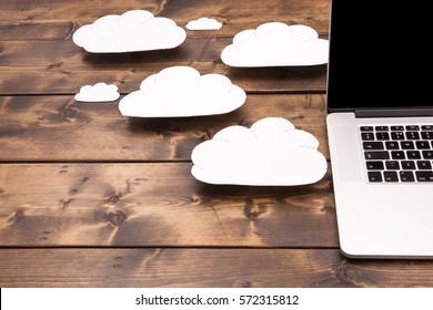 Cloud computing concept laptop close up with white clouds coming out of the computer indicating online storage and internet connection.