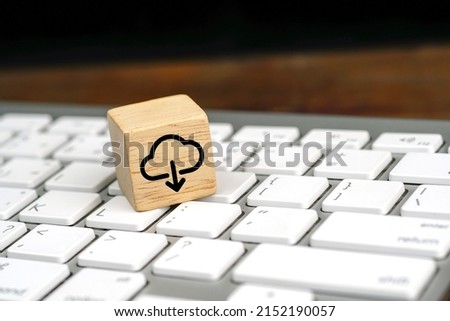 Cloud computing download icon on wooden cube on a white computer keyboard. Remote download technology concept.                 