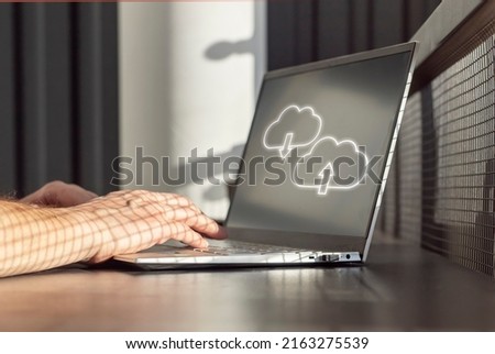 Cloud computing. Man using laptop for upload, storage, download or sharing files and data online. Male hands on computer keyboard closeup. High quality photo
