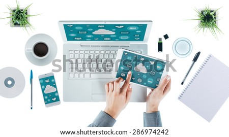 Cloud computing and multiplatform concept, user interface on laptop, tablet and smartphone, female hands touching an icon