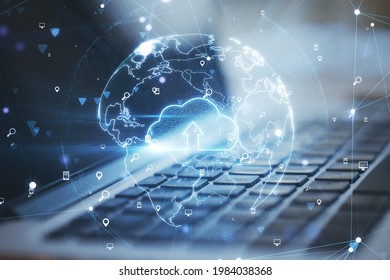 Cloud computing online storage concept with hologram cloud icon in the Earth planet model on laptop background. Double exposure
