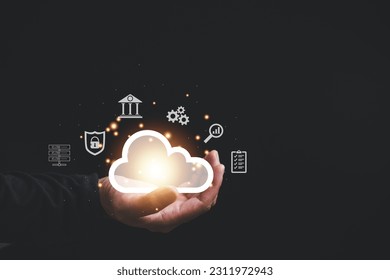 Cloud computing technology in action, a man access the server network holding cloud on hand on black background, and storage services with global marketing support, a concept for online businesses. - Shutterstock ID 2311972943