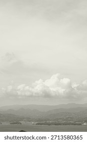 Cloud Dancer colored overcast sky with a few clouds above sea and mountains. Monochrome texture 2026. Color of the year