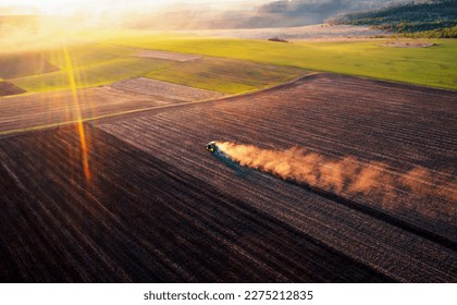 A cloud of dust rises behind a tractor plowing the ground. Spring soil preparation for sowing crops. Agrarian region of Ukraine, Europe. Aerial photography. Industry of agronomy. Beauty of earth. - Shutterstock ID 2275212835