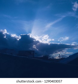 A cloud formation shielding the sun which produces rays of sunlight above a residential area