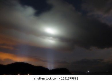Cloud glows at night by the light from the bridge behind the island