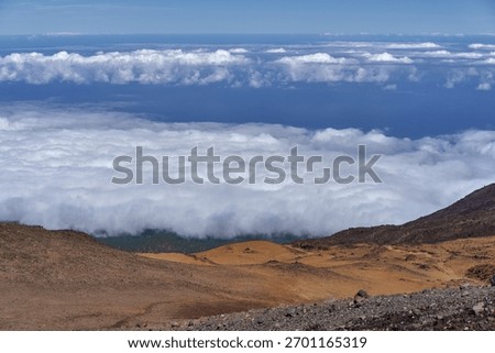 Cloud inversion seen from the volcanic slopes of Teide with dense white clouds below and arid rocky terrain in sunlight above