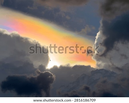 Cloud iridescence is a phenomenon where clouds radiate a beautiful pastel rainbow of colors as a storm brews in the dark, gloomy sky.