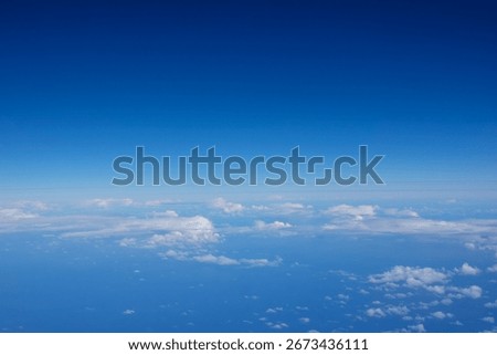 Cloud pattern between blue sea below and sky above through plane window while travelling.