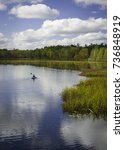 Cloud reflections dance across the smooth surface of a North Woods lake as a kayaker enjoys a pleasant autumn afternoon in northern Wisconsin.