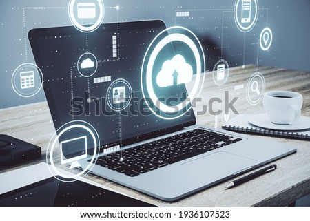Cloud service technology concept with digital data storage icons and opened laptop with coffee cup on background. Double exposure