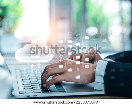 Cloud technology concept. Cloud icons with folders and document files showing on screen while businessperson working with laptop computer. Data storage security, digital privacy secure on internet.