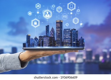 La tecnología de nube en el concepto de ciudad inteligente con mano humana lleva tableta digital con rascacielos de la ciudad de megapolis y símbolos de redes sociales digitales arriba en el fondo borroso del horizonte