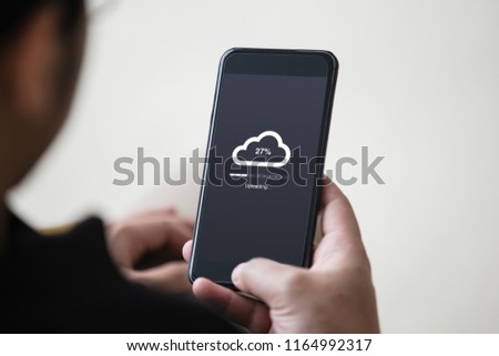Cloud uploading concept on phone screen. Man hand hold phone doing cloud uploading.