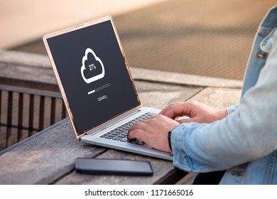 Cloud uploading concept on screen. A man is working using laptop doing cloud uploading at outdoor.