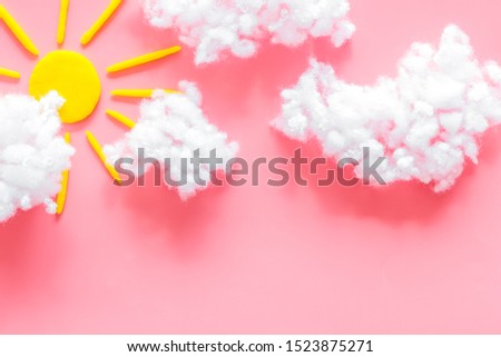 Cloudly weather concept. Sun and clouds on pink background top view copy space
