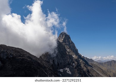 Clouds accumulating around the sharp mountain peaks of the Chaukhi massif in the Greater Caucasus Mountain Range in Georgia, Kazbegi Region. Mountain Ridges, Hiking. Georgian Dolomites. Cloudscape