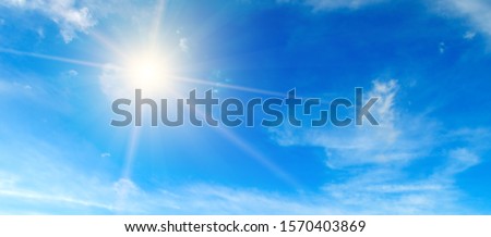 Clouds in the blue sky. Bright midday sun illuminates the space. Wide photo .